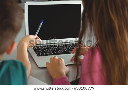 School kids using laptop in library at school