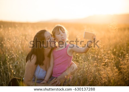 Daughter and mother sticking out tongue while capturing selfie