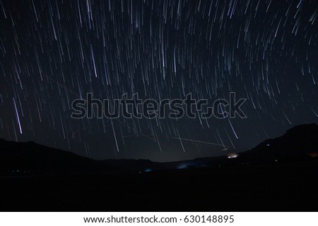 Night sky star trails comet effect with mountains