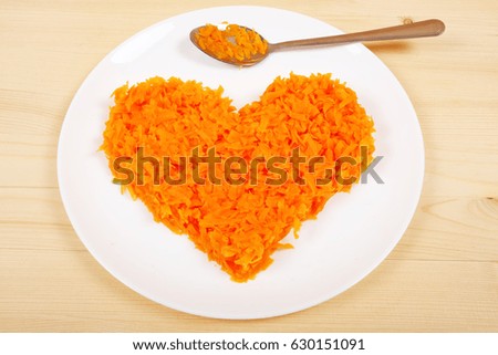 Boiled carrots in the form of heart on a white plate wooden background