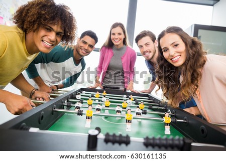 Happy executives playing table football in office Royalty-Free Stock Photo #630161135