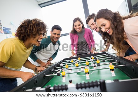 Happy executives playing table football in office Royalty-Free Stock Photo #630161150