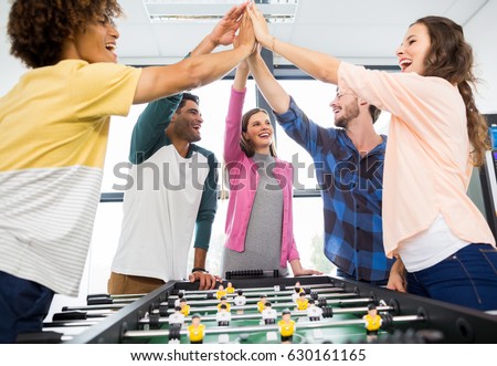 Executives giving high five while playing table football in office Royalty-Free Stock Photo #630161165