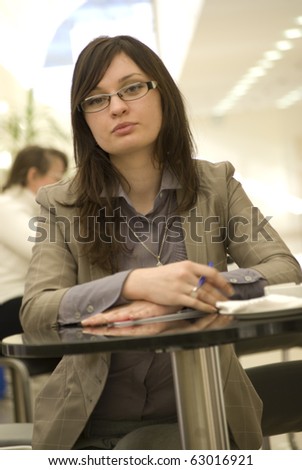 Portrait of a cheerful Business woman sitting on her desk holding a pen reading and signing documents