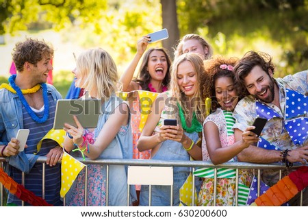 Friends clicking pictures from their mobile phones and digital tablet in park