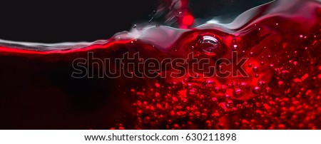 Red wine on black background, abstract splashing. Macro shot .