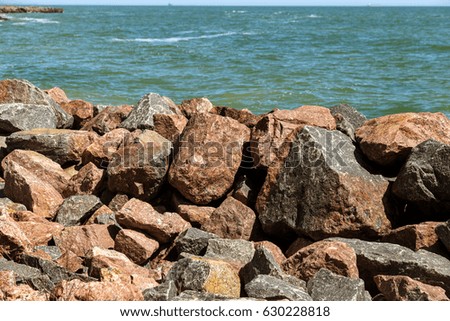 Heap Granite stones on beach. Granite stone wave surging barrier of Big boulder on beach. Chaotic, messy abstract Background of wild granite rough Stone. Artificial Stone Ridge, breakwater