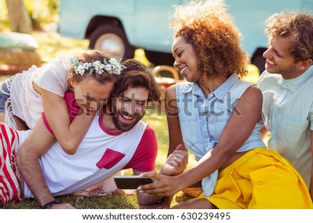 Group of happy friend using mobile phone in park