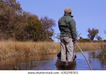 Man in a mokoro canoe in the Okavango Delta, Botswana; Concept for travel in Africa and Safari