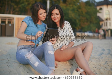 girl in the sunny city sitting on the sand and enjoy the tablet