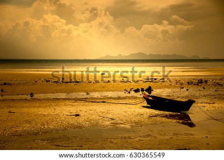 Silhouette of boats with an orange tropical sunset/A small boat on the beach at sunset. The sun is setting, there is golden light on the water.