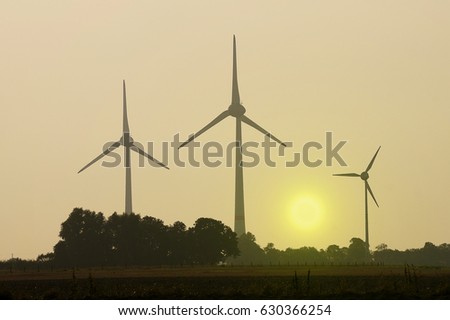 three windmills in the sunrise. picture taken in germany near the north sea coast.