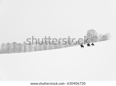 Black and white photograph of snowy field with trees and horse riders