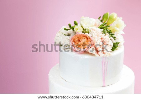 Closeup of wedding cake decorated with fresh roses, carnations and freesia 