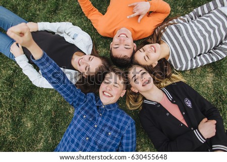 Teenage boys and girls lying in the grass on a summer holidays.