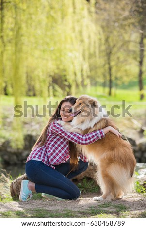 Young beautiful woman with long hair in an embrace with a collie dog. Outdoors in the park.