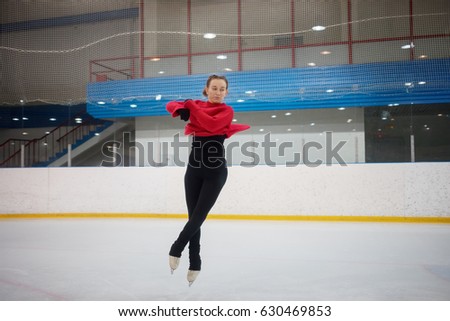 Young slim dancing woman during jump on skate in indoor ice rink