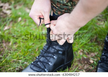 german soldier laces his boots on grass