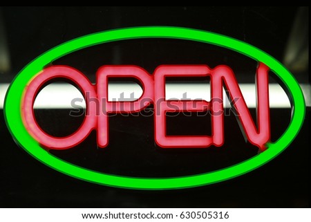 Retro neon sign that says open inside a green glowing oval