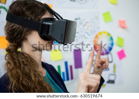 Female graphic designer using the virtual reality headset in creative office