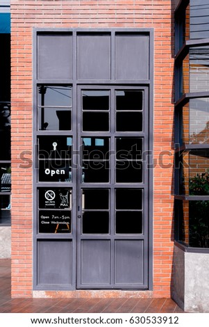 gray iron doors with glass and orange brick.and sign 