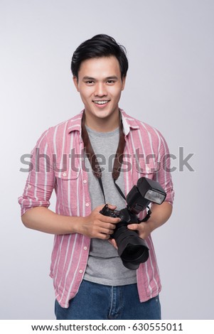 Young asian photographer holding digital camera, while working in studio