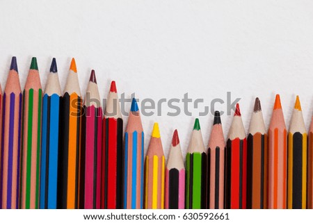 Close-up of colored pencils arranged in a wave pattern on white background