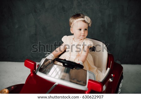 Cute baby girl dressed as bride play with toy retro car