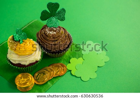 St Patricks Day shamrock on the cupcake with gold coins on green background