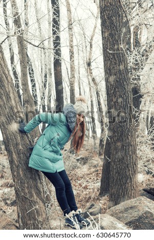 Girl is standing among the trees in snow winter park. Toned and processing photo