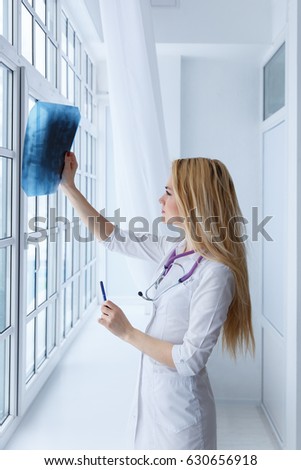 Young female doctor looking at the x-ray picture in hospital. Health care and prevention concept.