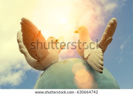 Monument of peace - two white pigeons against a blue sky with clouds, Toned photo