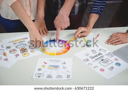 Mid section of graphic designers interacting with each other while working in office