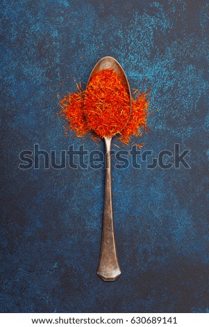 Saffron in an old silver spoon on a blue background. View from above.