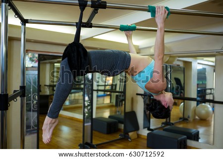 Determined woman performing stretching exercise on pilates cadillac in gym