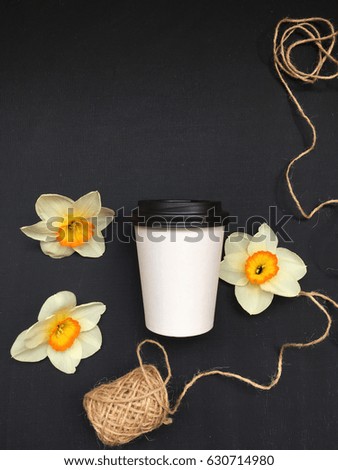 concept spring coffee with daffodils on black background with space for your text. spring coffee take away. spring white cup go away. 