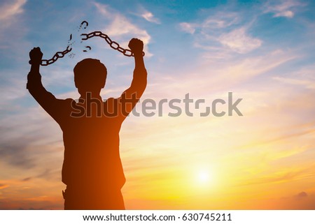 Silhouette image of a businessman with broken chains in sunset Royalty-Free Stock Photo #630745211