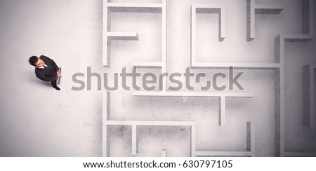 Confused businessman standing at a maze wall with grungy background
