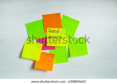 Set of multicolored stickers or sheets of paper on a white wooden background. The inscription Good morning on the sticker in the center. Horizontal.