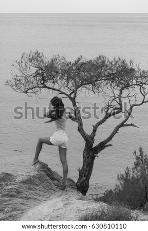 Black and white photo of attractive girl by the tree on the mountain peak