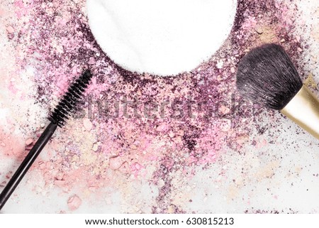 Closeup of makeup brush and mascara applicator on white marble background, with traces of powder and blush forming frame. Horizontal template for makeup artist's business card, with copy space