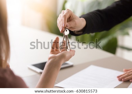 Young lady taking keys from female real estate agent during meeting after signing rental lease contract or sale purchase agreement. Independent woman purchasing new home, close up view Royalty-Free Stock Photo #630815573