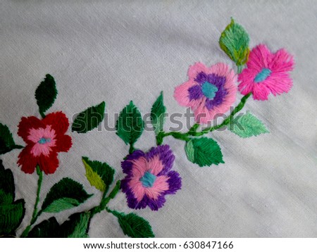 Beautiful Ukrainian hand embroidery. Embroidered flowers in retro style on white fabric. Blossoming branch. Design of folk embroidery