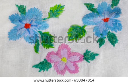 Beautiful Ukrainian hand embroidery. Embroidered flowers in retro style on white fabric. Design of folk embroidery