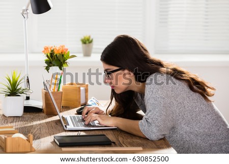 Businesswoman Sitting In Wrong Posture Working On Laptop On Wooden Office Desk Royalty-Free Stock Photo #630852500