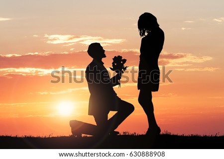 Silhouette Of A Man Proposing His Girlfriend Against Dramatic Sky At Sunset