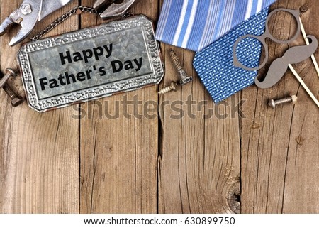 Happy Fathers Day message on metal sign with top border of tools and ties on a wooden background
