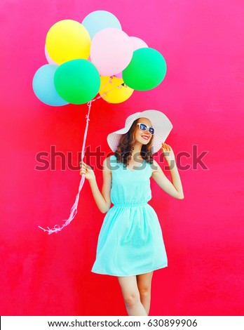 Fashion happy pretty smiling woman with an air colorful balloons is having fun in summer on a pink background