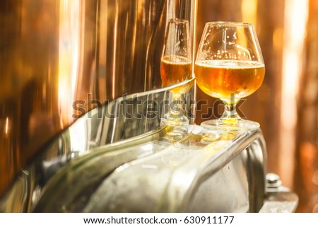 Glass with amber ale beer standing on a metal doorway of a copper lauter tun at a brewery Royalty-Free Stock Photo #630911177