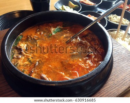 Spicy Korean soup bowl. Spicy noodles soup with meat. Korean spicy soup. Korean soup with meat and mushrooms in black dish. The Korea food Sundubu. Korean soups warmed in pot.  Spicy Fish Roe Soups